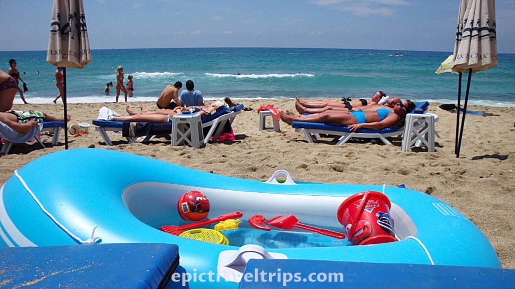 Kleopatra Beach with people laying on the beach and blue gummy boat.