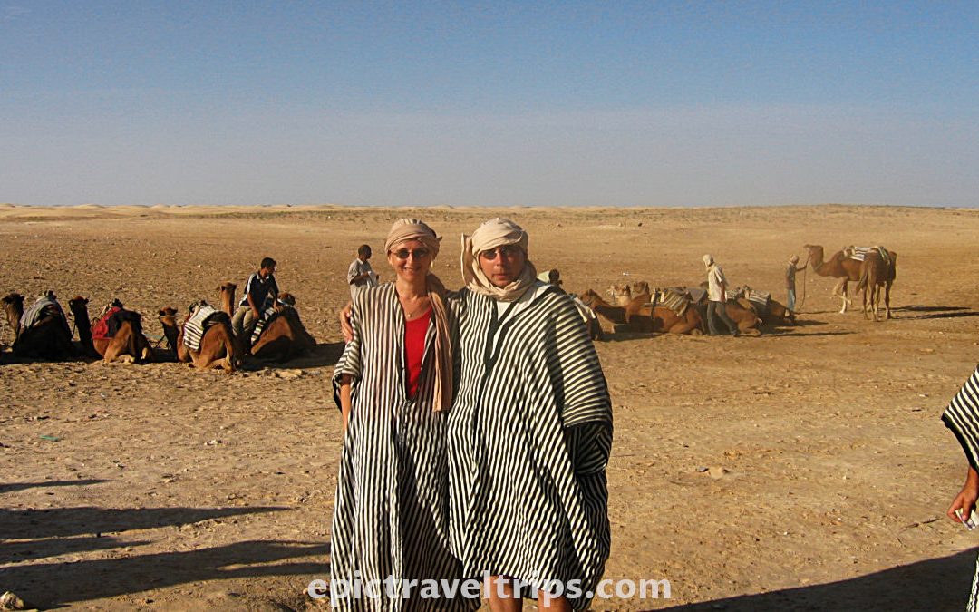Camels parked at the back and couple dressed as bedouins in Sahara desert at Zaafrane, Tunisia. Part of our Adventurous Three Days Epic Sahara Tour In Amazing Tunisia With Hidden Gems.