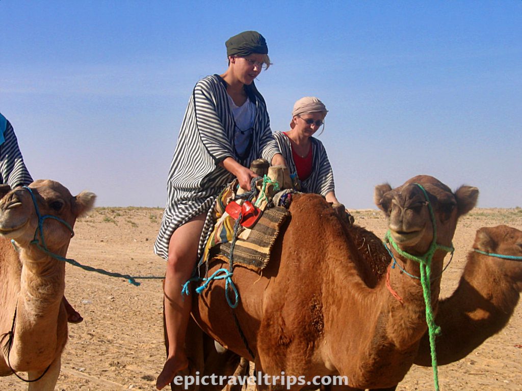 Two women riding camels in Zaafrane, Tunisia. Part of our Adventurous Three Days Epic Sahara Tour In Amazing Tunisia With Hidden Gems.