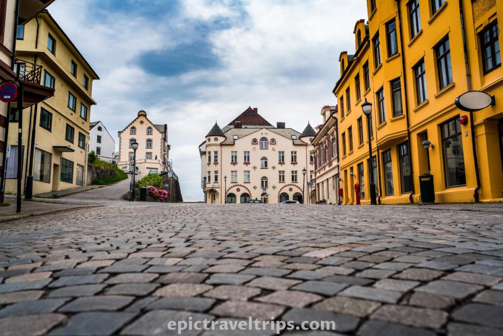 Cobblestone street with colorful Art Nouveau architecture buildings in Ålesund in Norway.