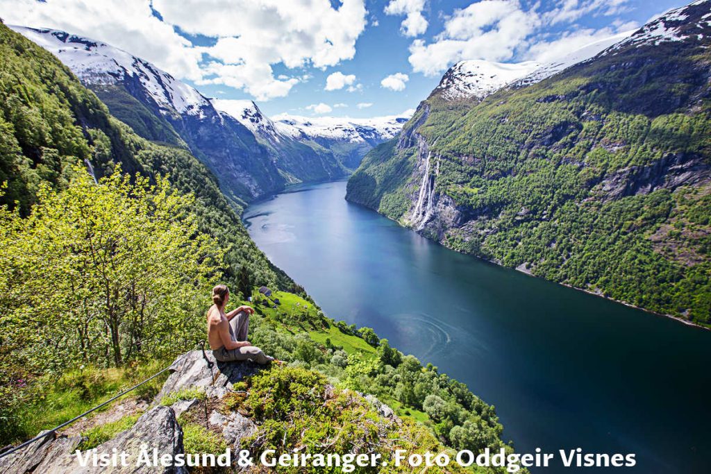 Girl on the cliff with a view over Geiranger fjord and Seven Sisters waterfalls from Skageflå mountain farm in Norway.
