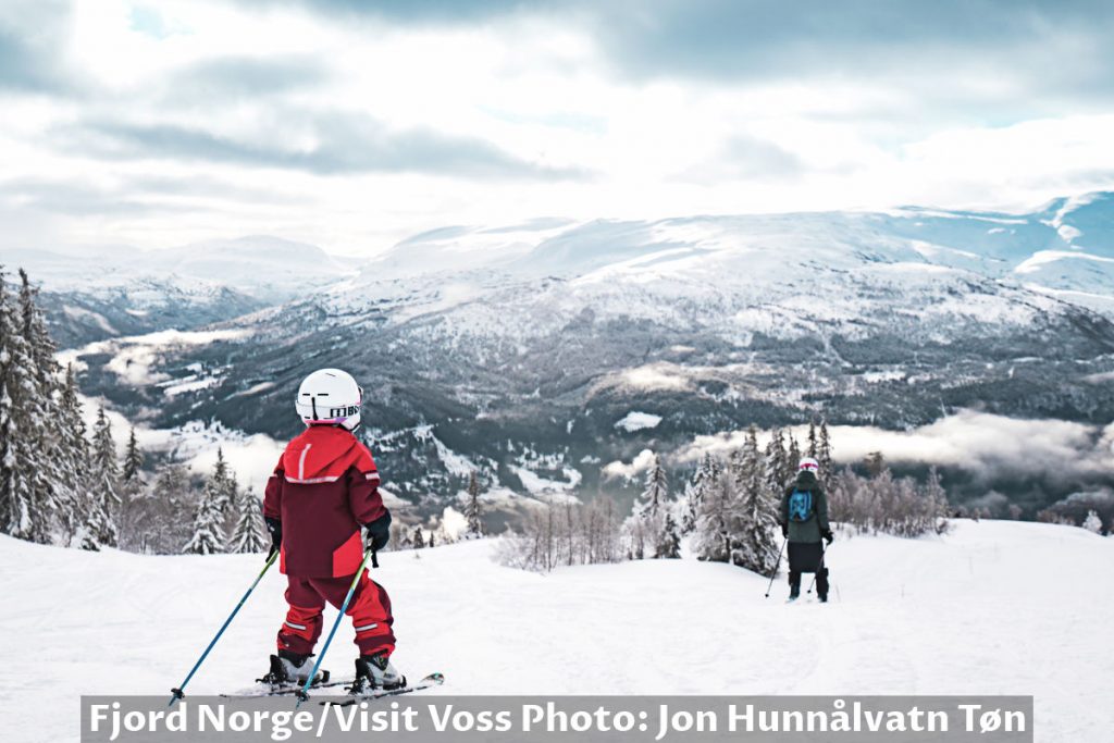 Kid and person ski down the slope near Voss in Norway.