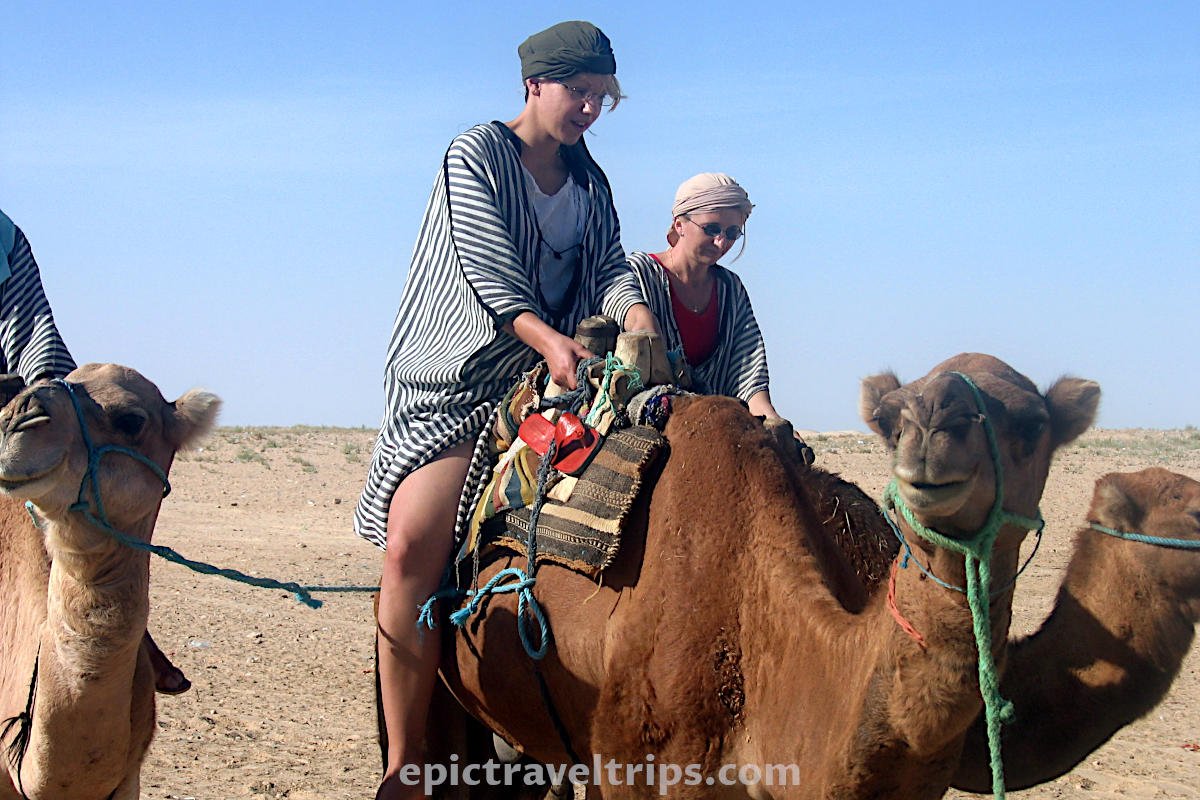 Two women ride camels in the Sahara desert at Zafran in Tunisia