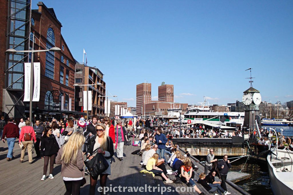 Aker Brygge pedestrian zone with lots of people in Oslo city center near City Hall building and fjord in Norway.