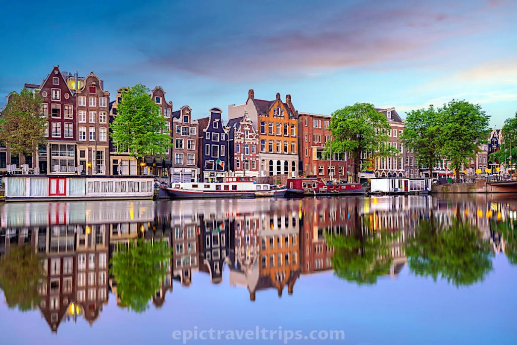 Amsterdam skyline and canal with boats during sunset in The Netherlands.