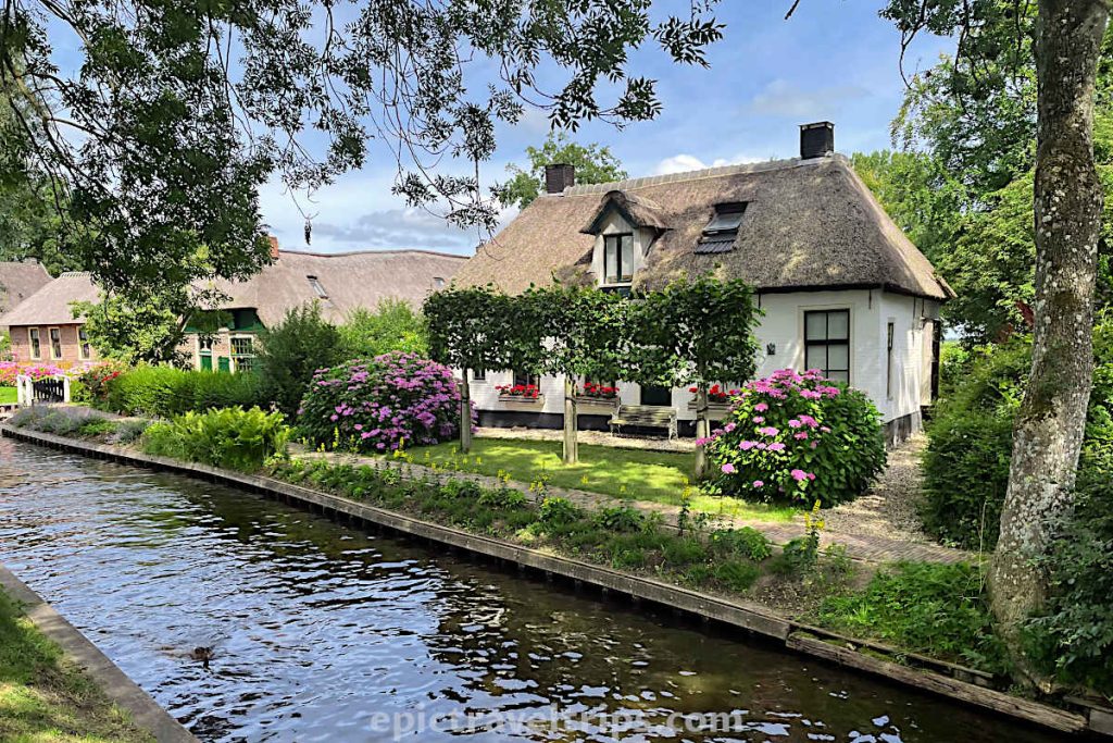 Beautiful white house with trees and a garden in front at Giethoorn Village in The Netherlands